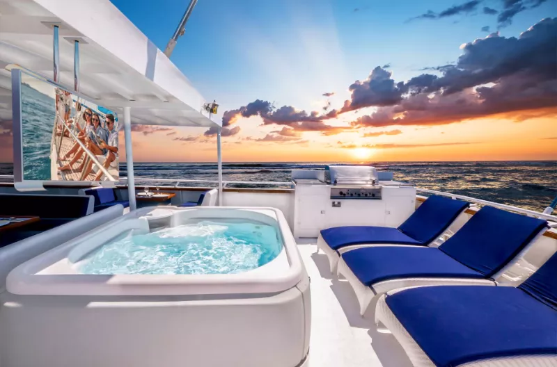 A perfect view of sunset in a yacht with ceiling mounted outdoor TV and overlooking waves.
