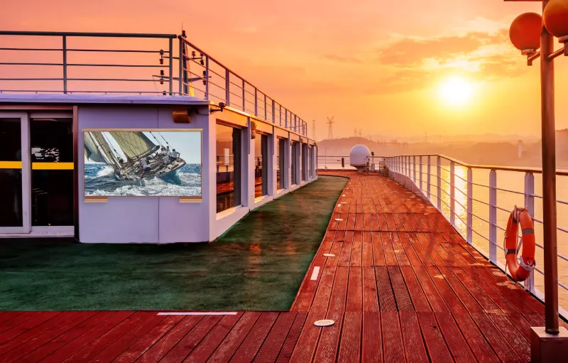 A beautiful sunset over a calm ocean with vibrant sea and an outdoor TV on the left corner.